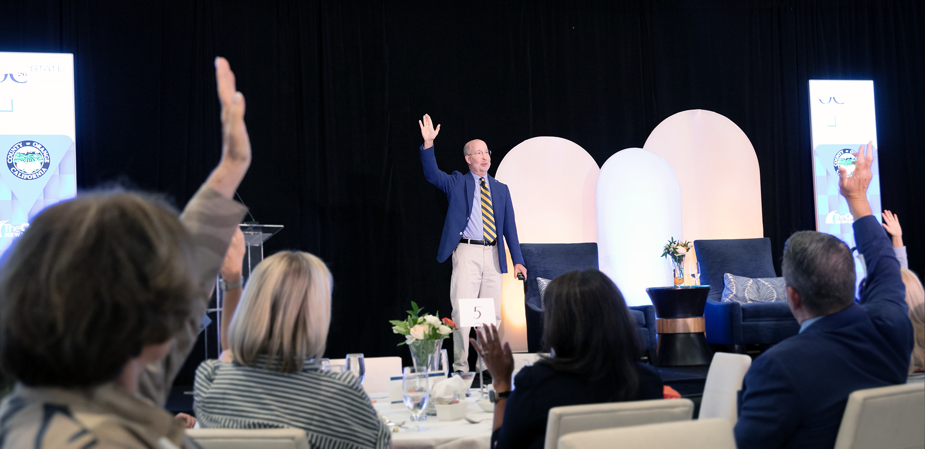 Jon Gould on stage raising his hand