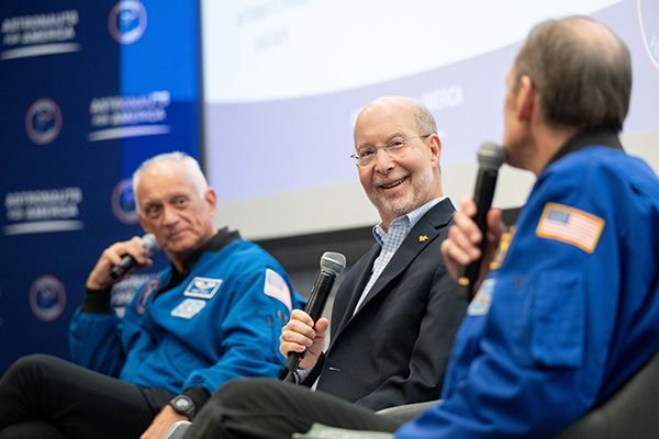 Jon Gould between two astronauts on stage
