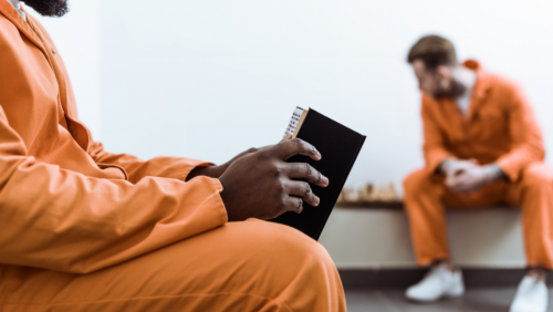 Prisoner reading a book and a prisoner playing chess in the background