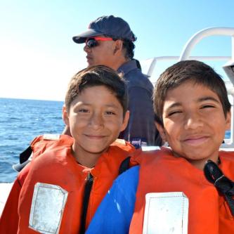 Two boys in life jackets on a boat floating at sea.