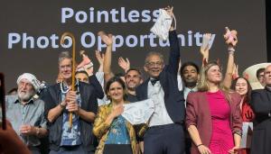A group of people posing in front of a sign that reads pointless photo opportunity